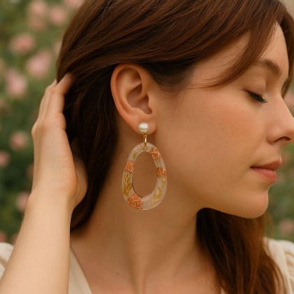 Σκουλαρίκια οβάλ με λεπτομέρειες φυλλώματος και φύλλων χρυσού φορεμένο